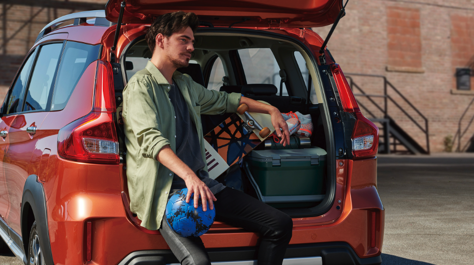 Man sitting in back of Suzuki xl7 with trunk open